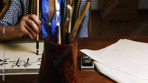 Girl writes Chinese characters (Translation from Chinese Mandarin 1: jixiang ruyi wanshi ankang- to be gratified propitiously with everything in good health, 2: fugui jixiang: wealthy and propitious) photo