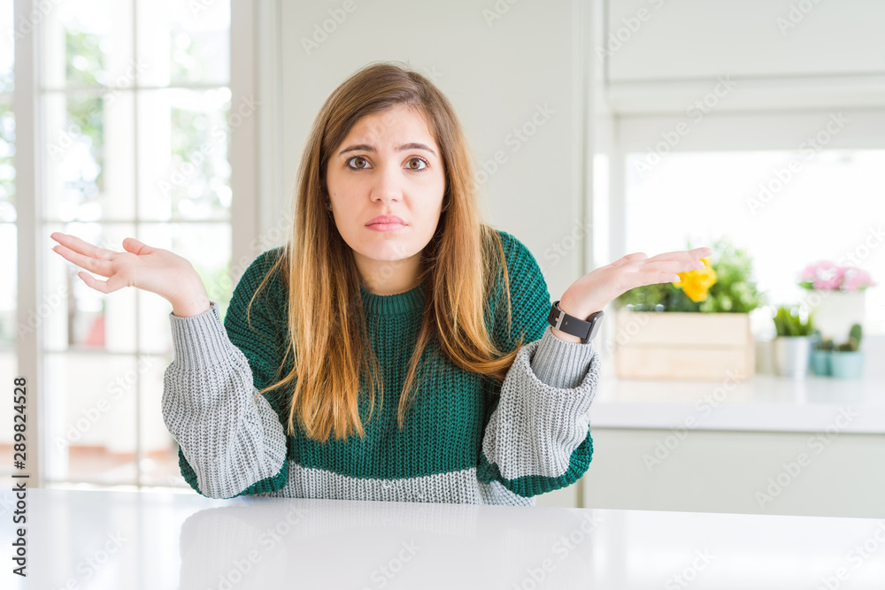 Young beautiful plus size woman wearing casual striped sweater clueless and confused expression with arms and hands raised. Doubt concept. Young beautiful plus size woman wearing casual striped sweater clueless and confused expression with arms and hands raised. Doubt concept.