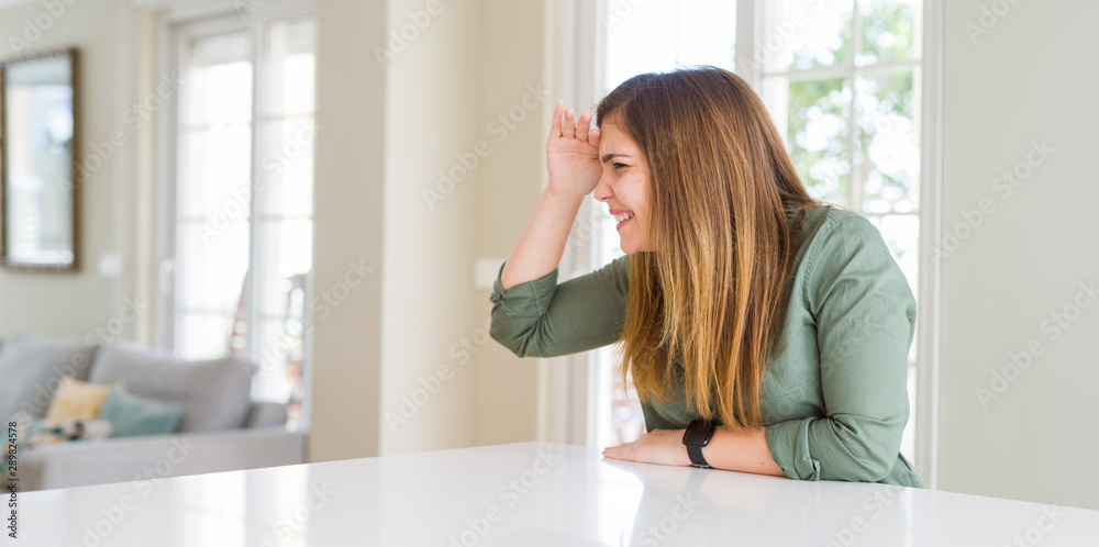 Beautiful young woman at home very happy and smiling looking far away with hand over head. Searching concept. Beautiful young woman at home very happy and smiling looking far away with hand over head. Searching concept.
