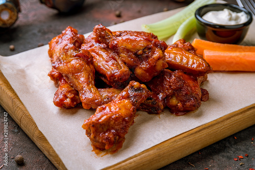 chicken wings in barbecue sauce and with blue cheese sause on dark rustic concrete table photo