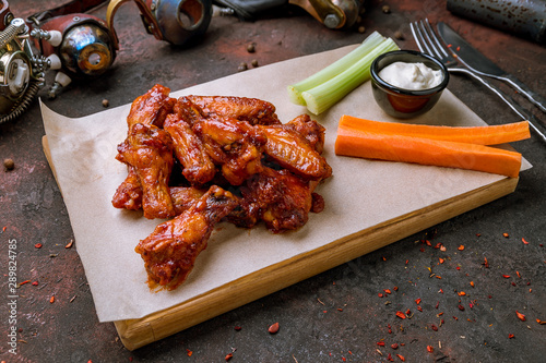 chicken wings in barbecue sauce and with blue cheese sause on dark rustic concrete table