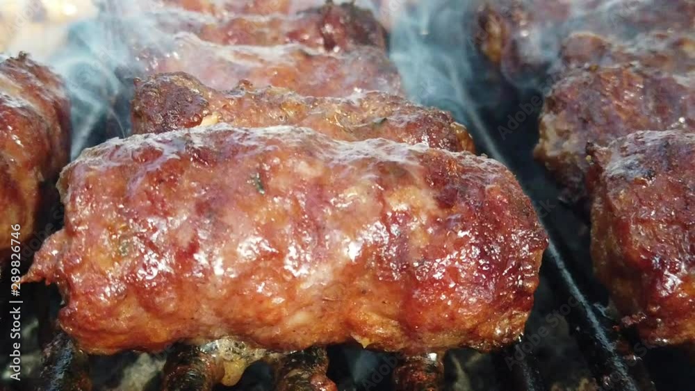Delicious looking meat cooking on a burning grill.Food cooking on a steaming barbeque in slow motion. Delicious looking meat cooking on a burning grill.Food cooking on a steaming barbeque in slow motion.