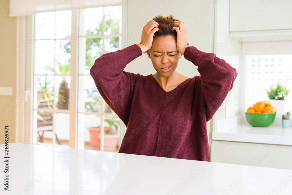 Young beautiful african american woman at home suffering from headache desperate and stressed because pain and migraine. Hands on head. Young beautiful african american woman at home suffering from headache desperate and stressed because pain and migraine. Hands on head.