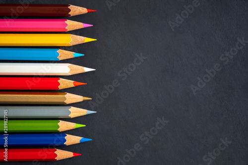 Colored pencils on chalkboard background. Top view and copy space. Concept of art education.