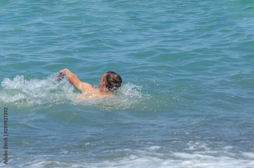 a man swims in the sea on a Sunny day; the concept of recreation, sports