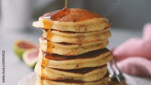 Syrup pouring on stack of american style buttermilk pancakes closeup view. Tasty sweet breakfast food