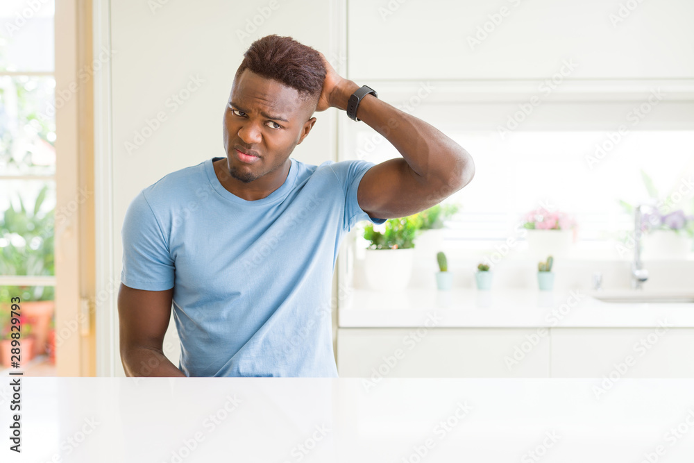 Handsome african american man wearing casual t-shirt at home confuse and wonder about question. Uncertain with doubt, thinking with hand on head. Pensive concept. Handsome african american man wearing casual t-shirt at home confuse and wonder about question. Uncertain with doubt, thinking with hand on head. Pensive concept.