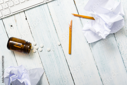 business stress concept, sedative pills and creased papers on work place table, top view photo