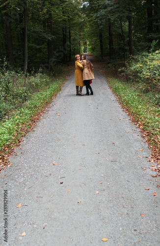 two people, mother and daughter, a woman and a young girl hold hands, walk in a yellow autumn park, throw up fallen leaves, the concept of family relationships, generations © kittyfly