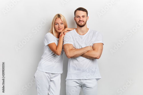 Young happy cheerful couple in white t-shirts posing to the camera on white background.fashion, beauty, people concept