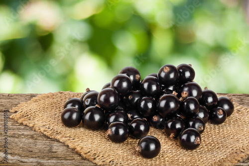 Black currants on burlap and wooden background