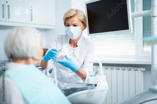 Female dentist is talking with mature patient