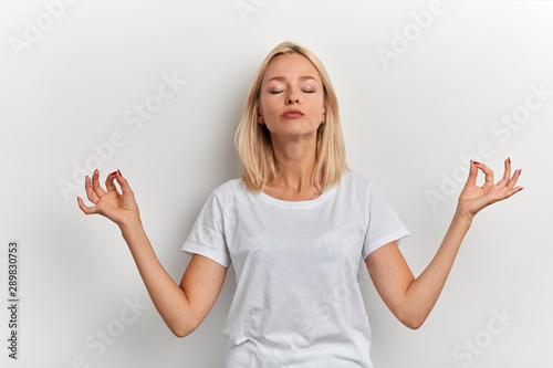 good looking awesome girl in white T-shirt enjoying yoga, close up portrait, isolated white background, studio shot,free time, spare time, girl relieves stress