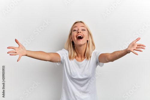 Portrait of a happy cheerful attractive young girl with outstretched hands going to embrace friend isolated on a white background, friendship, love