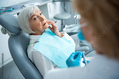 Adult woman with toothache sitting in dental chair