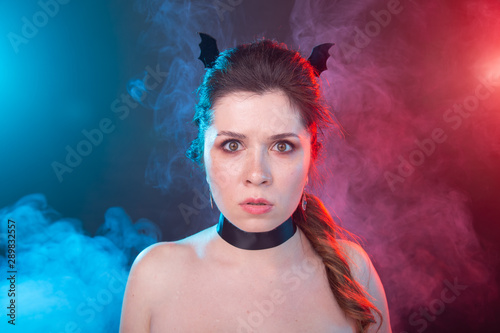 Halloween, holidays and carnival concept - portrait of woman in gothic style is looking very serious