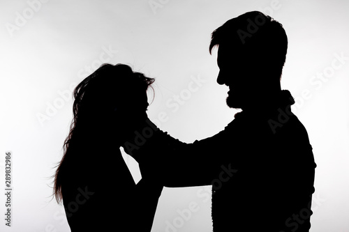 Domestic violence and abuse concept - Silhouette of man beating defenseless woman