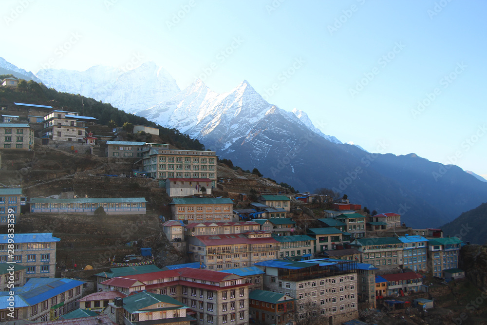 Cityscape of Namche Bazaar in the morning with Kasum Kanguru mountain in the background in Himalayas in Nepal. Outdoors, city view, bed and breakfast, mountains, hiking, travel and tourism concept.