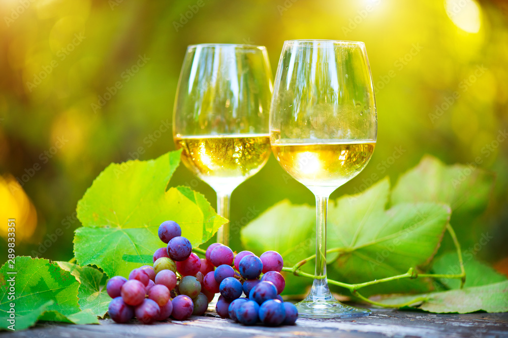 Wine. White Wine in wineglass. Romantic Dinner Outdoor. Wine tasting. Couple wine glasses and grapes close-up. Outdoors. Winemaking, winetasting