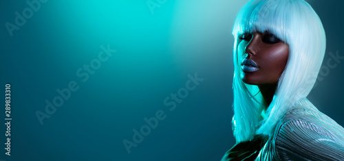 High Fashion model girl in colorful bright neon lights posing in studio, portrait of beautiful woman in white hair, wig and silver trendy glowing make-up. Glitter neon bright makeup