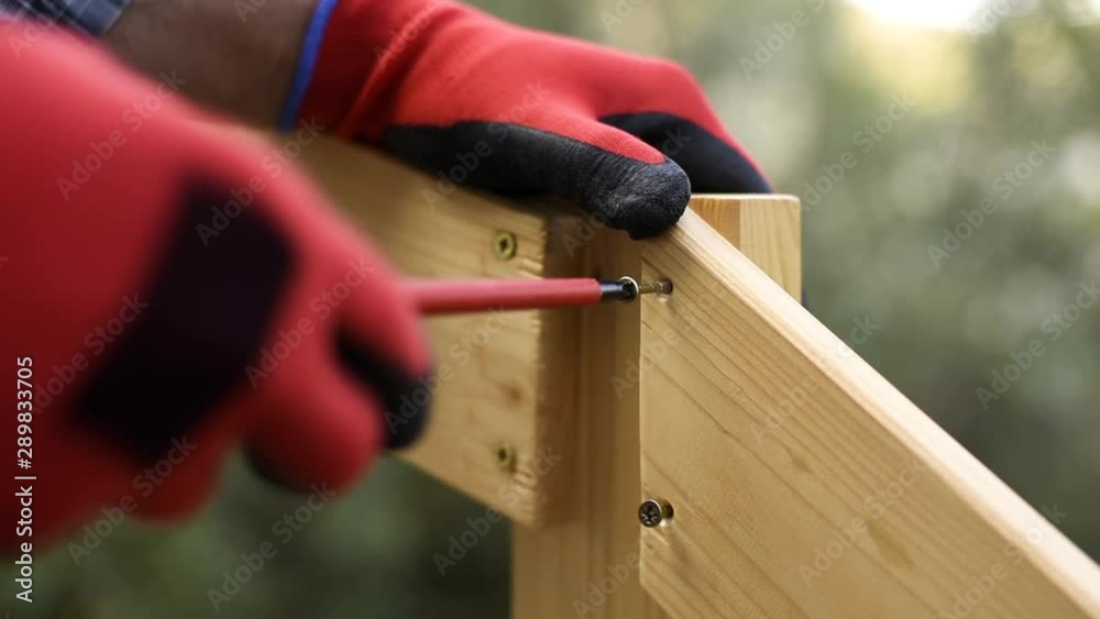 Adult carpenter craftsman with screwdriver screw the screw to fix the boards of a wooden fence. Housework, do it yourself. Footage. Adult carpenter craftsman with screwdriver screw the screw to fix the boards of a wooden fence. Housework, do it yourself. Footage.
