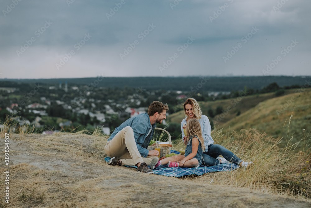 Happy young family is having picnic outdoors