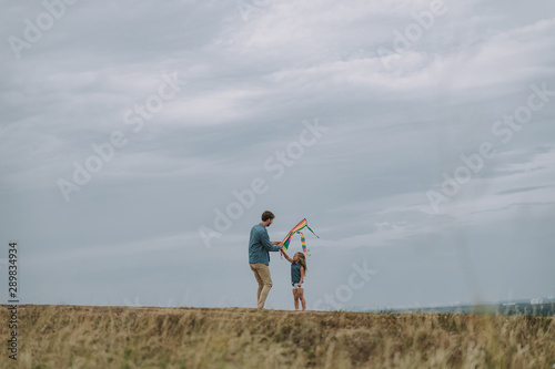 Young father is helping for kid with kite