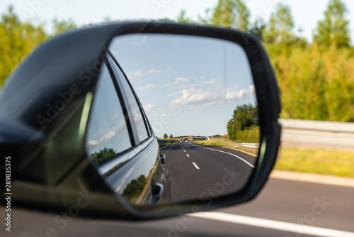 Asphalt road reflected in car mirror. Concept of safe driving.