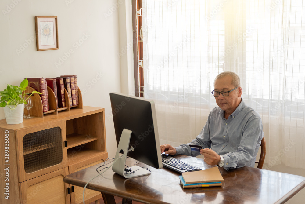 Senior man shopping online using computer and credit card.