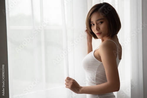 Attractive sexy asian woman standing near balcony window.