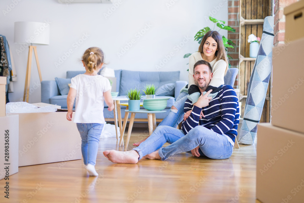 Beautiful family sitting on the floor playing with his kid at new home around cardboard boxes Beautiful family sitting on the floor playing with his kid at new home around cardboard boxes