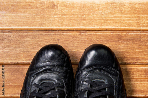 Fitness concepts- athletic shoes on wooden background. Old reliable black leather sneakers © Stanislau_V