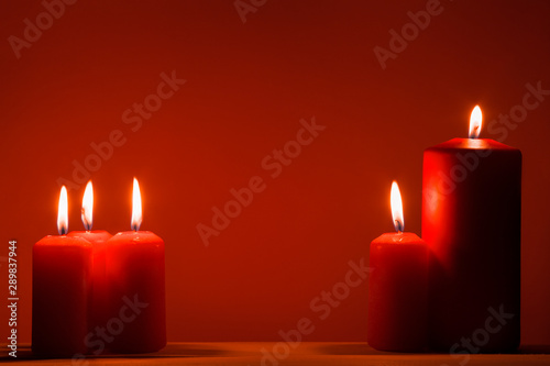 red burning candles on a red background. Christmas background.