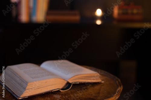 A book on a wooden table, with a dark background © LaSu
