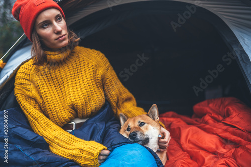tourist girl hug resting dog together in campsite, close up portrait red shiba inu sleeping in camp tent , hiker woman leisure with puppy dog relax nature vacation, friendship love concept