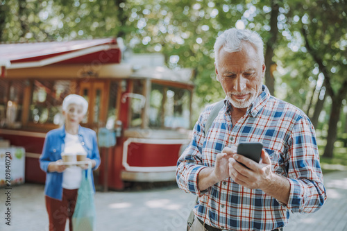 Smiling mature man with smartphone in the street stock photo
