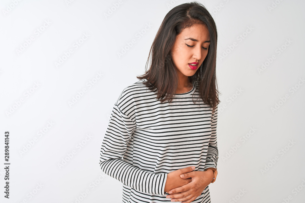Young beautiful chinese woman wearing striped t-shirt standing over isolated white background with hand on stomach because nausea, painful disease feeling unwell. Ache concept. Young beautiful chinese woman wearing striped t-shirt standing over isolated white background with hand on stomach because nausea, painful disease feeling unwell. Ache concept.
