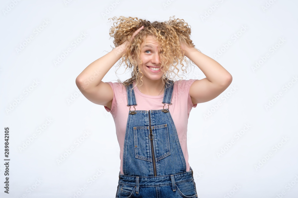 Youth and happiness concept. Beautiful caucasian curly girl looking at the camera, playing with her hair.