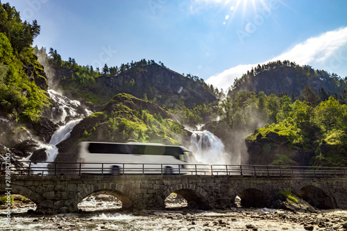 Tourist bus traveling on the road Latefossen Waterfall Odda Norway. Latefoss is a powerful, twin waterfall. photo