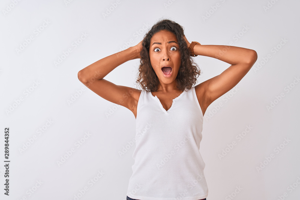 Young brazilian woman wearing casual t-shirt standing over isolated white background Crazy and scared with hands on head, afraid and surprised of shock with open mouth Young brazilian woman wearing casual t-shirt standing over isolated white background Crazy and scared with hands on head, afraid and surprised of shock with open mouth