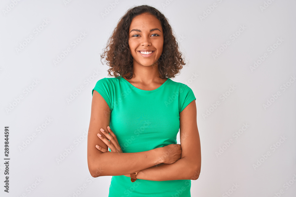 Young brazilian woman wearing green t-shirt standing over isolated white background happy face smiling with crossed arms looking at the camera. Positive person. Young brazilian woman wearing green t-shirt standing over isolated white background happy face smiling with crossed arms looking at the camera. Positive person.
