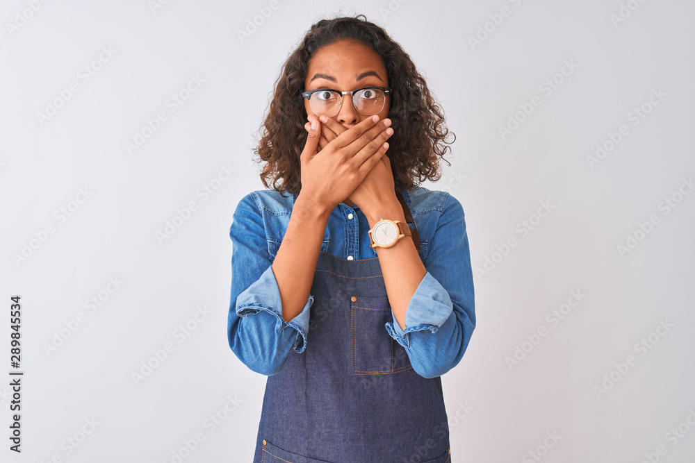 Young brazilian chef woman wearing apron and glasses over isolated white background shocked covering mouth with hands for mistake. Secret concept. Young brazilian chef woman wearing apron and glasses over isolated white background shocked covering mouth with hands for mistake. Secret concept.
