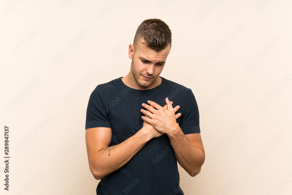 Young handsome blonde man over isolated background having a pain in the heart Young handsome blonde man over isolated background having a pain in the heart