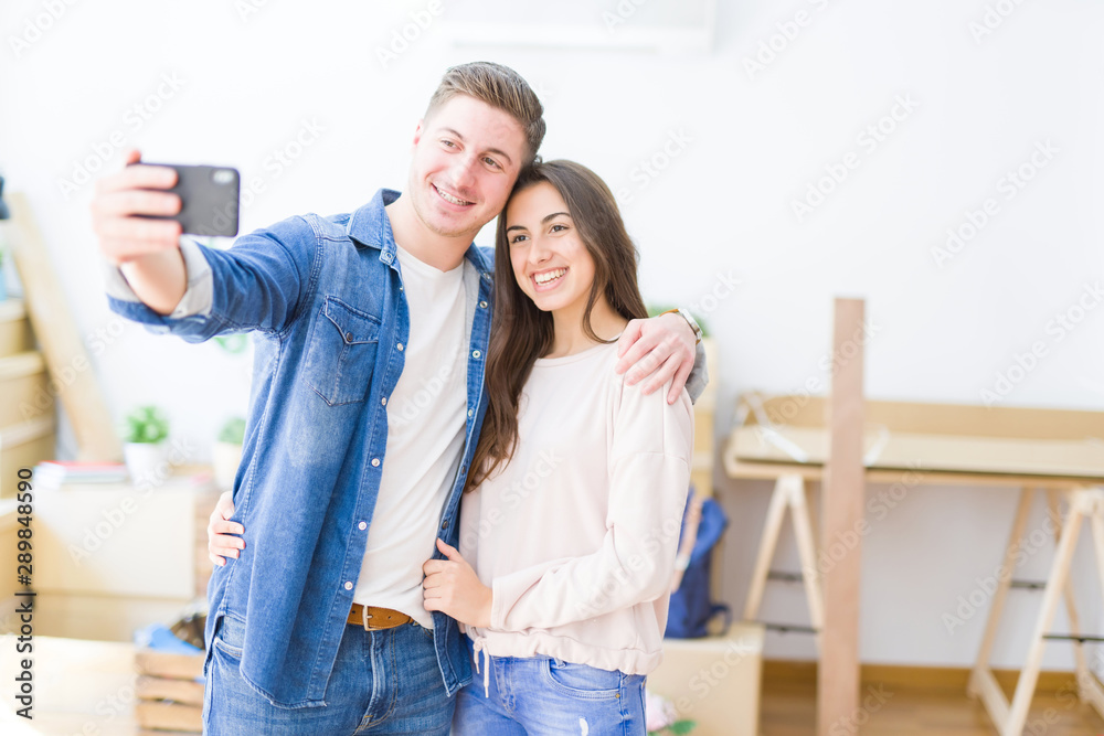 Beautiful young couple smiling happy taking a selfie photo with smartphone, very excited moving to a new home Beautiful young couple smiling happy taking a selfie photo with smartphone, very excited moving to a new home