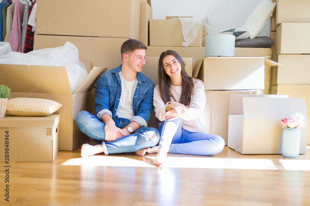 Young beautiful couple relaxing sitting on the floor around cardboard boxes at home, smiling happy moving to a new house Young beautiful couple relaxing sitting on the floor around cardboard boxes at home, smiling happy moving to a new house