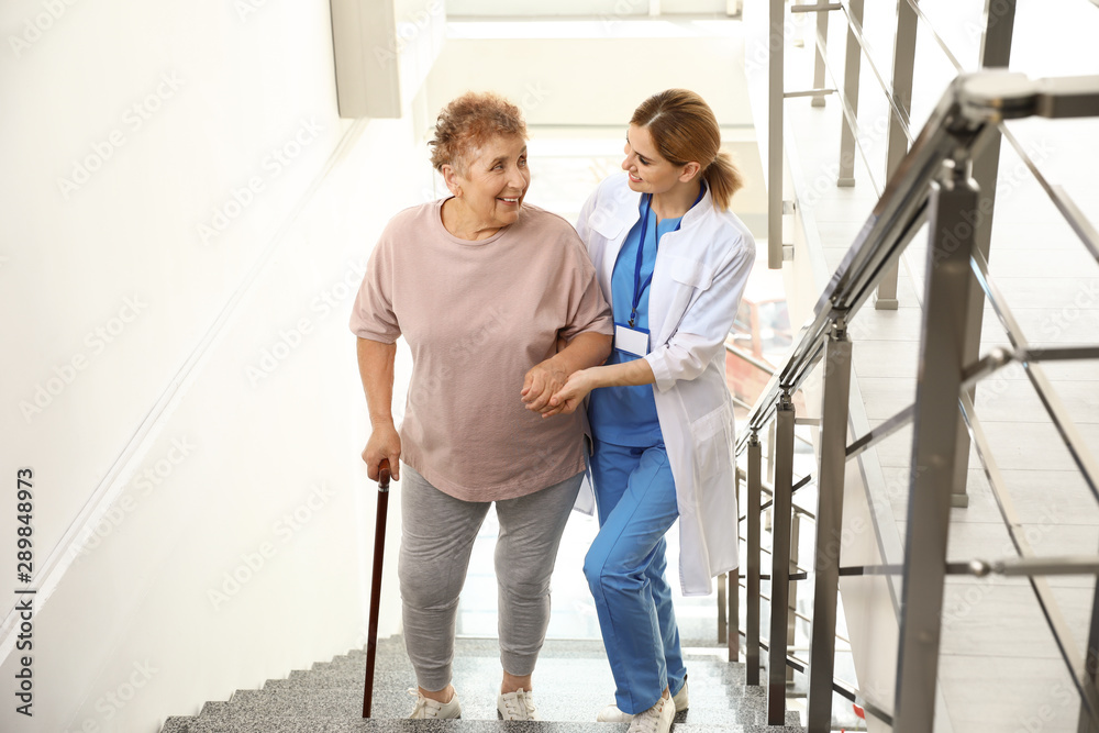 Nurse assisting elderly woman on stairs indoors Nurse assisting elderly woman on stairs indoors