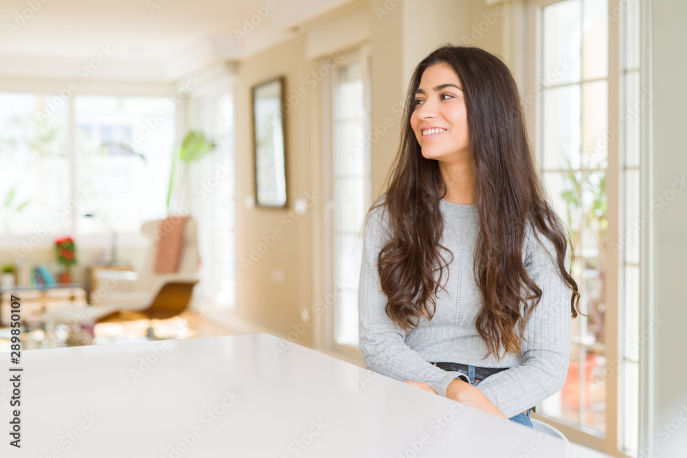 Young beautiful woman at home looking away to side with smile on face, natural expression. Laughing confident. Young beautiful woman at home looking away to side with smile on face, natural expression. Laughing confident.