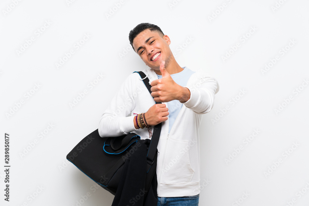 Sport man over isolated white wall with thumbs up because something good has happened Sport man over isolated white wall with thumbs up because something good has happened