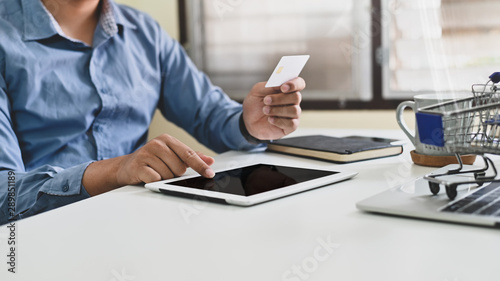 Closeup man using tablet and looking security code on credit card  Empty screen tablet and clipping path.