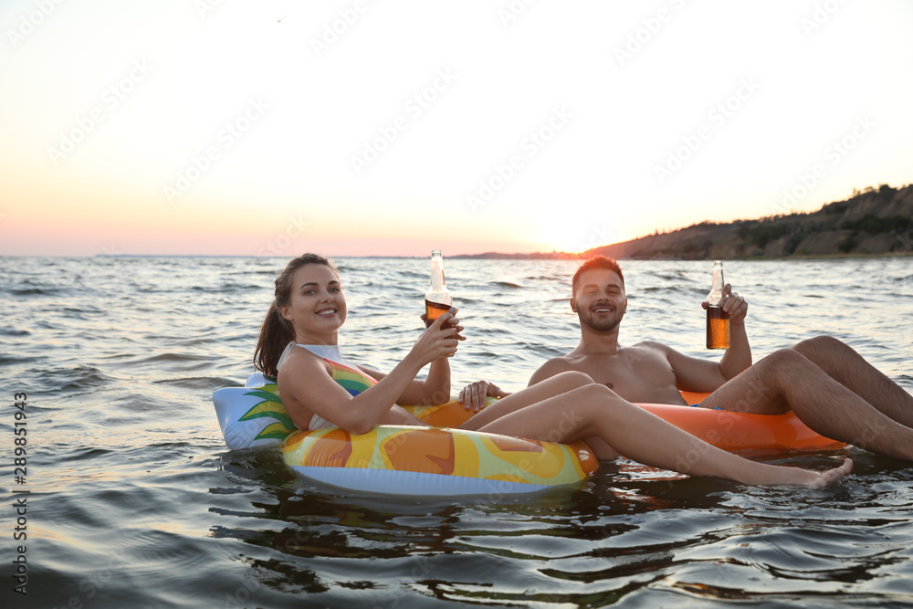 Obraz premium Happy young couple on inflatable rings in water